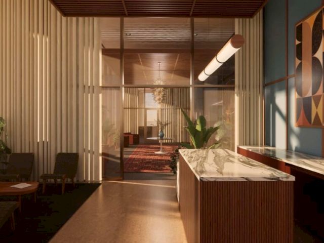 A modern office lounge with warm wood slats, plants, a desk, and an illuminated corridor.